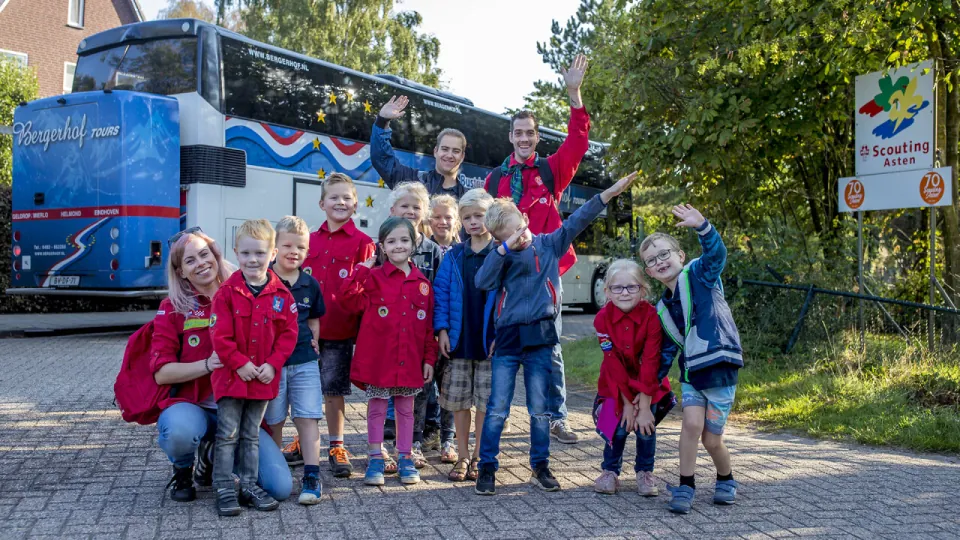 Een groep met leden en 2 leiding staan te zwaaien