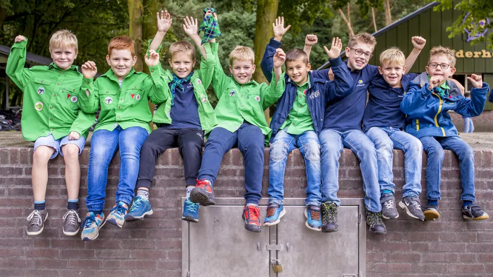 6 leden zitten zwaaiend op een rij