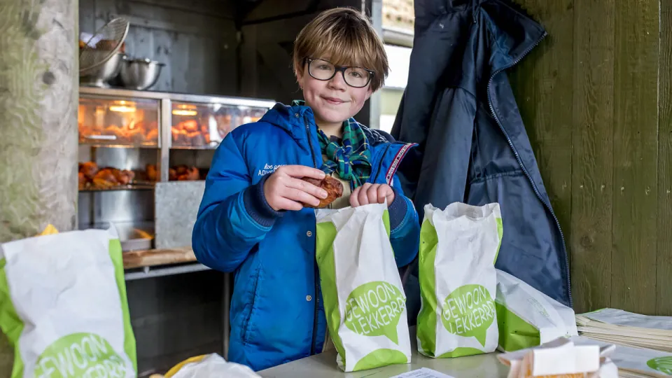 Een lid vult 2 zakken met oliebollen