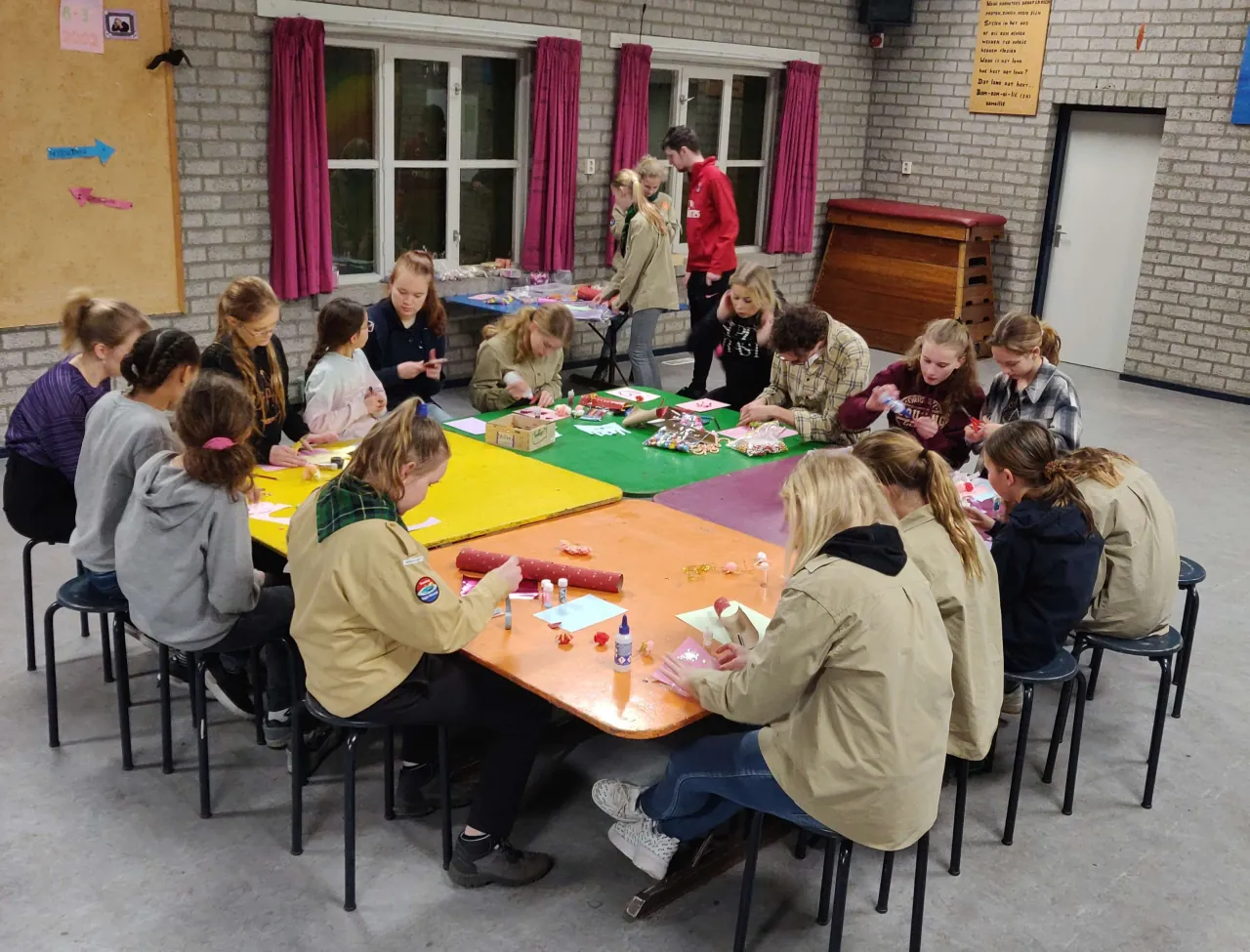 Een groep kinderen zit te knutselen rond een grote tafel