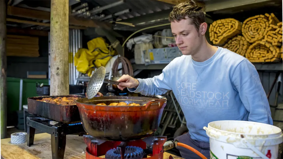 Een leider staat oliebollen te bakken