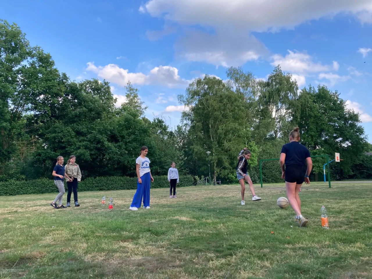 Een groep kinderen speelt voetbal op een grasveld
