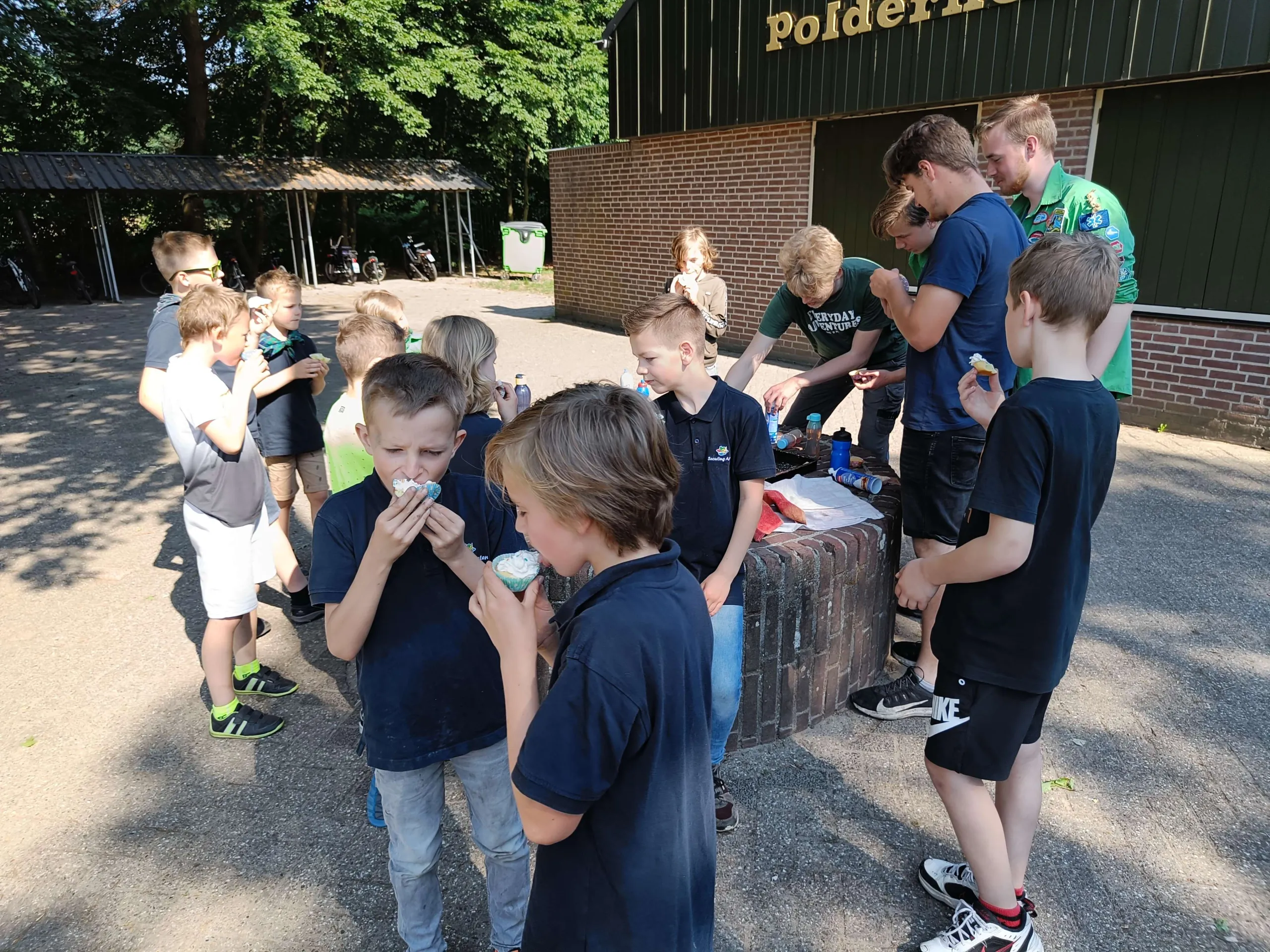 Een groep jongens eten cupcakes voor de blokhut